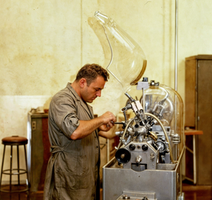 A factory worker diligently manages a machine, showcasing the precision and effort involved in industrial operations.