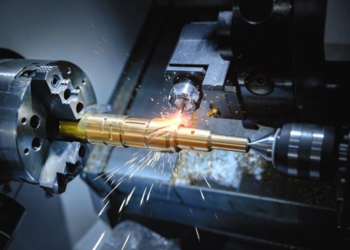 A CNC lathe precisely cuts a metal component, generating sparks in the process of metalworking.