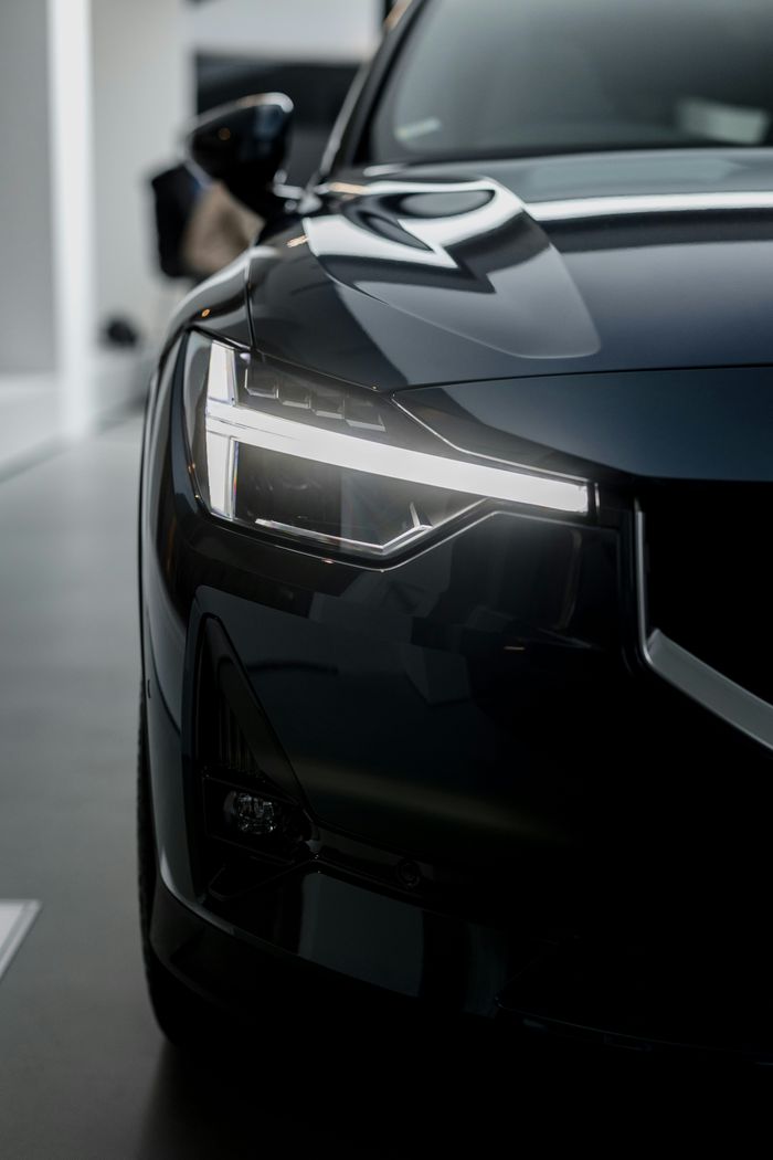 A sleek black sports car parked, showcasing its aerodynamic design and shiny exterior under bright sunlight.