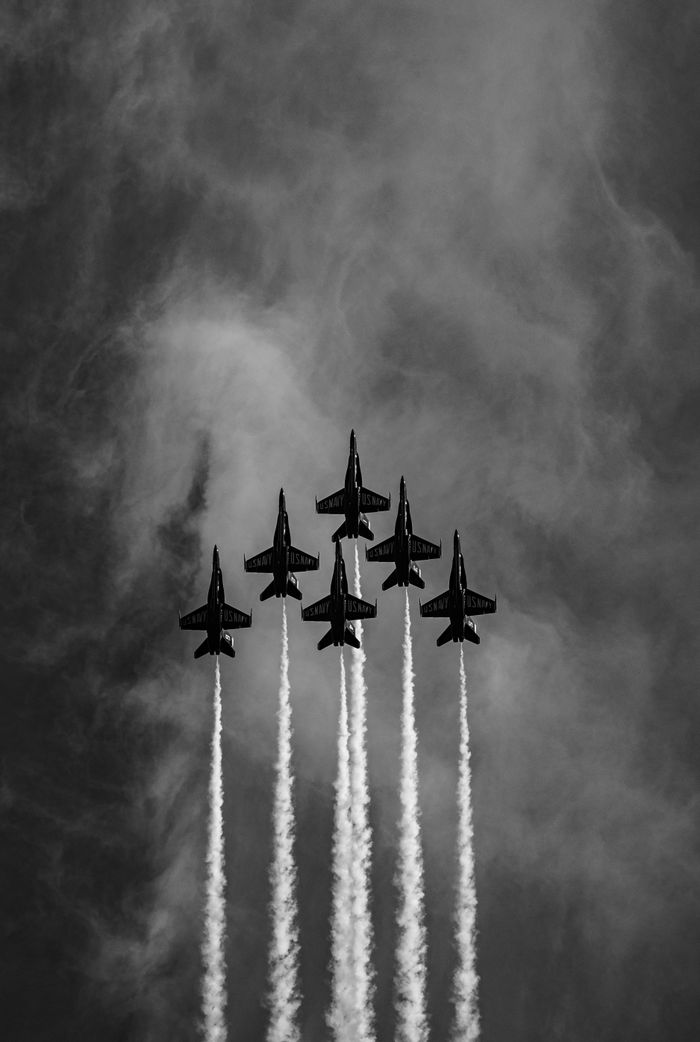 A black and white photograph depicting four jets flying in precise formation against a clear sky backdrop.